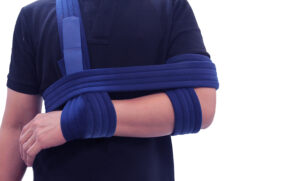 Man in blue shirt wearing shoulder immobilizer sling
