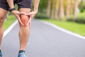 Young male jogger clutching his painful knee