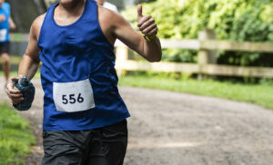 A long distance runner gives a thumbs up during a race on a trail in the woods