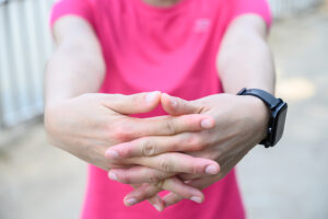 Athletic woman wearing bright pink top performing hand and finger exercises