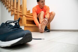 Male runner with his sneaker off rubbing his painful foot
