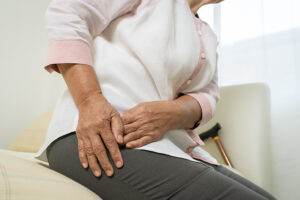 Elderly women sitting on couch holding her painful hip