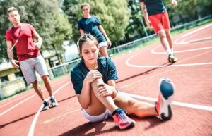 Young female runner sitting on track with knee injury