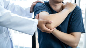 Orthopedic physician examining male patient's shoulder