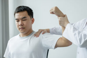 Orthopedic physician examining male patient's painful shoulder
